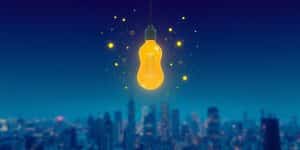 Lightbulb illuminating a stylized cityscape.