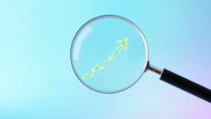 Magnifying glass over upward trending arrow